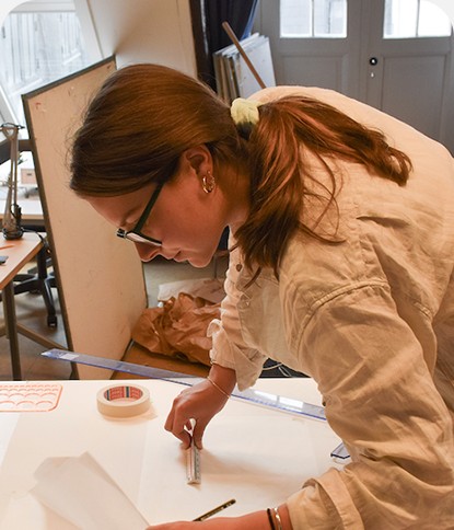 Designer working on printed layouts at a studio desk